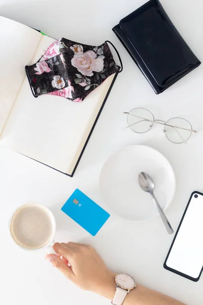 女性的手捧着一杯咖啡和牛奶 白桌子上的信用卡组成 平躺在地上 俯瞰四周 — 图库照片