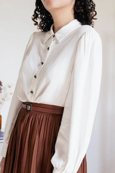 Young pretty woman in pleated skirt, white shirt on white background. Fashion vintage inspired clothes look.