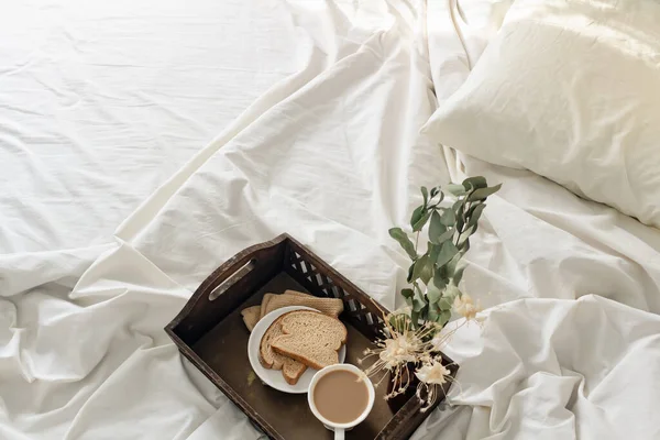 早上浪漫早餐的概念 新鲜切片面包 床上放一杯咖啡 薄薄的米色薄片和枕头 — 图库照片