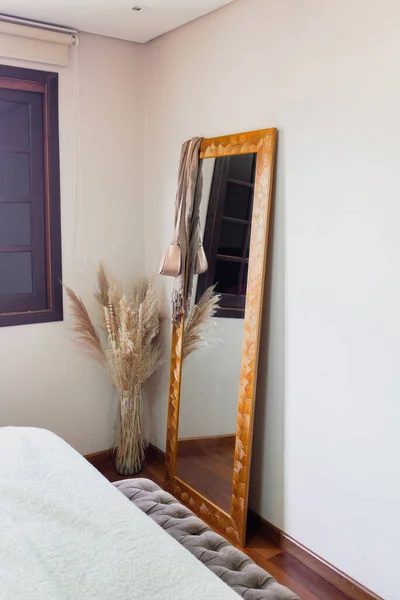 Stylish bedroom with mirror and bouquet of dried flowers. Modern classic design.