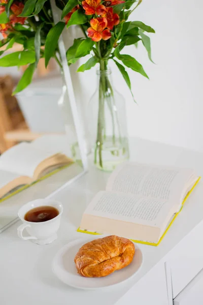 クロワッサンと朝の朝食 開いた本と紅茶のカップ — ストック写真