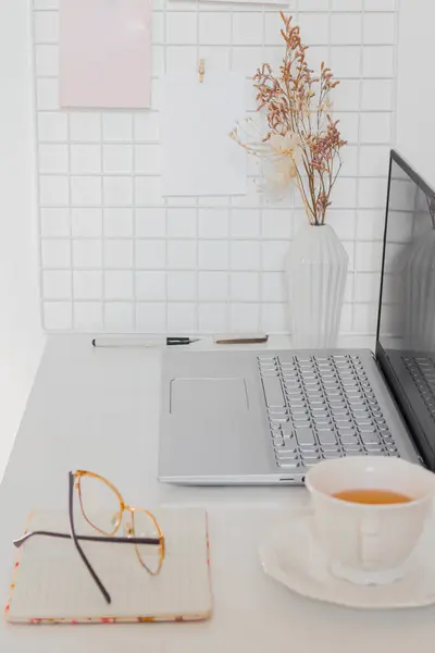 Business concept. Minimalist home office desk with laptop, cup of tea and stationary supplies