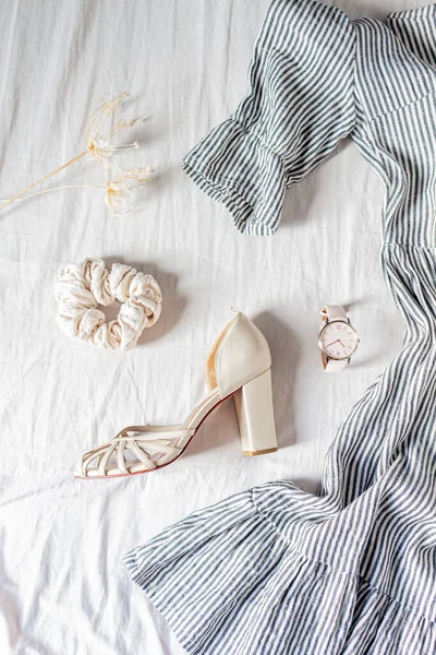 漂亮的时尚平平平静静地躺在女人的衣服 一个扇贝 一个腕表 高跟鞋和一朵干花在白色的棉布上 顶级时尚博客生活方式概念 — 图库照片