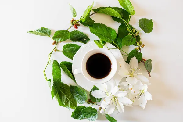 一杯用白花和黑莓叶装饰的黑咖啡的顶部视图 — 图库照片