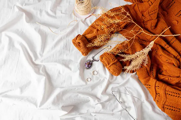 女性ファッションコンポジション 暖かい女性のウール編まれたセーター 金のリング 乾燥した植物 サイザルロープ メガネ 白いベッドシートの背景にお茶 秋の作曲について — ストック写真