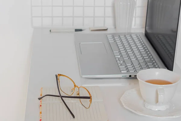 Business concept. Minimalist home office desk with laptop, cup of tea and stationary supplies
