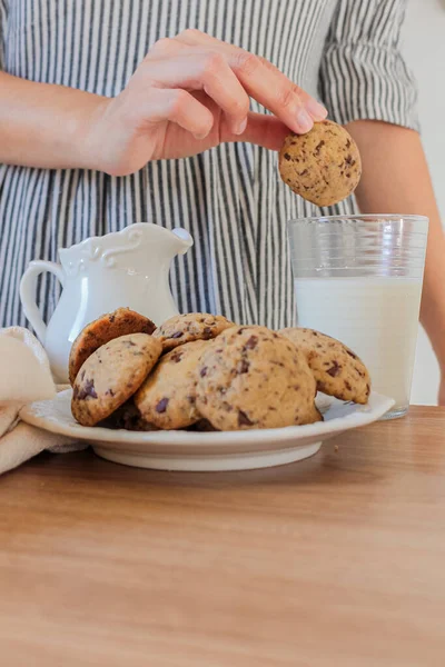 Cropped shot of woman eating cookies and drinking milk