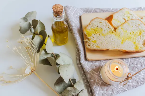 白色面包片 顶部涂上橄榄油 用蜡烛和桉树干叶制成木板 — 图库照片