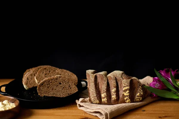 Celý Nakrájený Hnědý Chleba Dřevěný Stůl Zdobený Květinami Temné Složení — Stock fotografie
