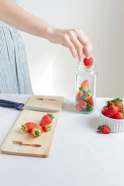 年轻的女人把草莓放在罐子上 有机食品储存概念 — 图库照片