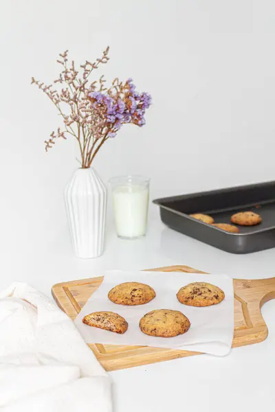 木制切菜板上的自制饼干和白色背景上的一杯牛奶 — 图库照片