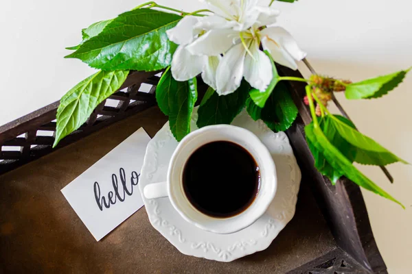 黑色咖啡杯放在盘子里 卡片上写着 白花和黑莓树叶子在白色的背景上 春天的概念 — 图库照片