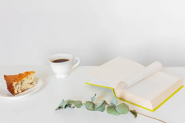 Breakfast composition with coffee, book, piece of cake on white background.  Slow morning routine concept.