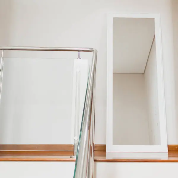 Large mirror with wall reflection leaning on the wall close to stairs. Scandinavian home.