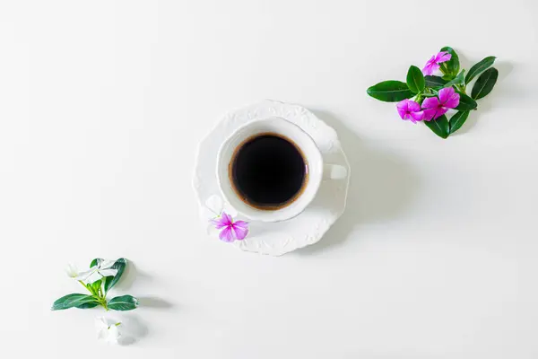 白色背景的紫色花朵的黑咖啡杯的顶部视图 — 图库照片