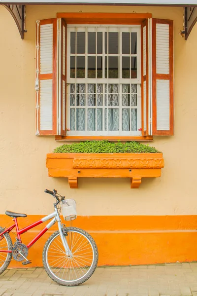 橘子屋 色雷斯塔和白色窗户下面有一个花盆 白色和红色的自行车靠在墙上 骑自行车在秋天的下午 — 图库照片