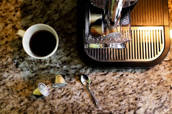 espresso machine with used coffee capsules and cup of americano on a table