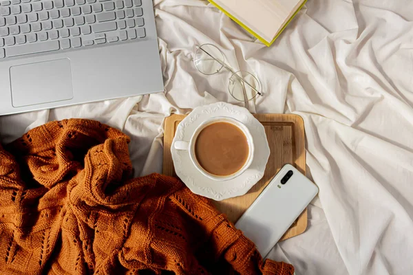 사무용품을 사무실 노트북 목걸이 스웨터 우유를 커피의 지저분한 침대에 — 스톡 사진
