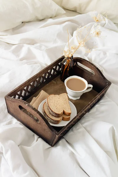 早餐在黑暗的木制复古托盘在床上与米色薄片和枕头 浪漫的早晨概念 — 图库照片