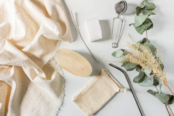 Beige eco style feminine household supplies: coconut soap wooden cutting board and eucalyptus leaves on white background. Flat lay, top view. Eco friendly minimalist concept.