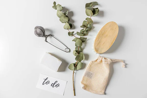Beige eco style feminine household supplies: cleaning brush, cotton bag, tea strainer, coconut soap, eucalyptus leaves and quote 