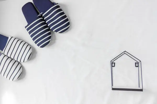 Zwei Paar Hausschuhe Und Ein Winziges Haus Auf Weißem Tuchhintergrund — Stockfoto