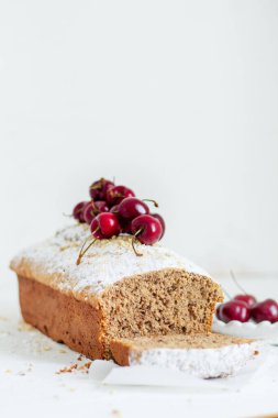 Beyaz arka planda kirazlı ev yapımı fındıklı kek. Estetik kahvaltı konsepti.