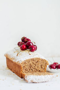 Beyaz arka planda kirazlı ev yapımı fındıklı kek. Estetik kahvaltı konsepti.