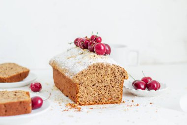 Beyaz arka planda kirazlı ev yapımı fındıklı kek. Estetik kahvaltı konsepti.