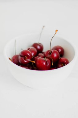 Beyaz arka planda, bir kasede vişne. Minimalist kompozisyon.