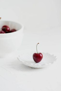Beyaz arka planda, bir kasede vişne. Minimalist kompozisyon.