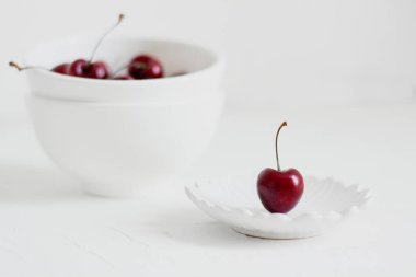 Beyaz arka planda, bir kasede vişne. Minimalist kompozisyon.