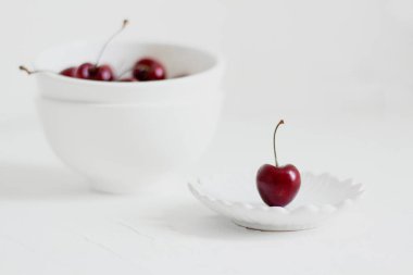 Beyaz arka planda, bir kasede vişne. Minimalist kompozisyon.