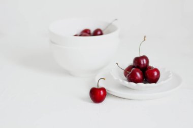 Beyaz arka planda, bir kasede vişne. Minimalist kompozisyon.