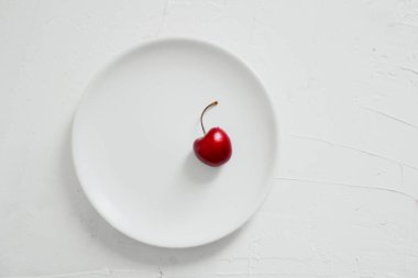 Beyaz arka planda, bir kasede vişne. Minimalist kompozisyon.