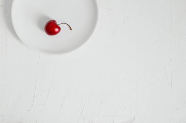 Beyaz arka planda, bir kasede vişne. Minimalist kompozisyon.