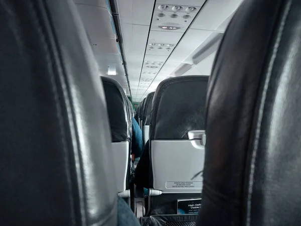 photo of row of seats in the plane full of people taken from behind of the middle seat