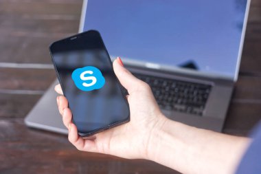 WROCLAW, POLAND - 2 Ekim 2023: Skype logosu, telekomünikasyon uygulaması, arka planda MacBook Pro ile iPhone ekranında görüntülendi