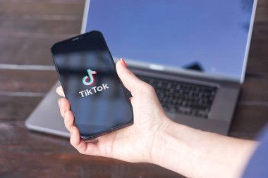 WROCLAW, POLAND - 14 Eylül 2023: Çin sosyal medya uygulaması - TikTok logosu arka planda MacBook Pro ile iPhone ekranında görüntülendi