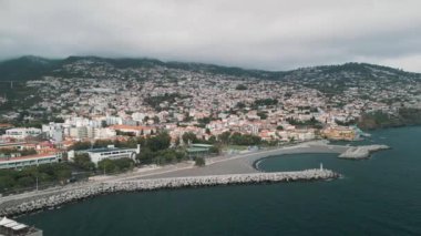 Portekiz 'in Madeira adasının başkenti Funchal şehir manzarasının insansız hava aracı videosu. Limanı ve arka planda dağları olan bir panorama.