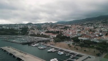 Portekiz 'in başkenti Madeira Adası' ndaki Funchal limanında yatları ve tekneleri olan insansız hava aracı videosu. Arka planda Eski Funchal Kasabası.