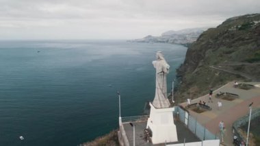Christo Rei (İsa 'nın Anıtı) ile birlikte Portekiz' in Canico yakınlarındaki Madeira Adası 'nda çekilmiş bir insansız hava aracı videosu. Körfezin panoraması. Arka planda Canico şehri.