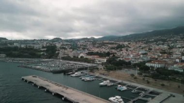 Portekiz 'in Madeira adasının başkenti Funchal şehir manzarasının insansız hava aracı videosu. Limanı ve arka planda dağları olan bir panorama.