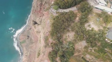 Portekiz 'in Madeira adasındaki Atlantik Okyanusu üzerindeki yaklaşık 600 metrelik uçurumda yer alan Cabo Girao bakış açısını ziyaret eden insanların insansız hava aracı görüntüsü. Uçurumdan yukarıdan aşağıya doğru.