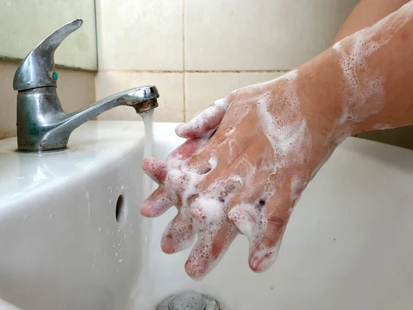 Women use liquid soap washing her hands. The World Health Organization (WHO) recommends social distancing, together with regular hand washing, is key in efforts to halt the spread of COVID-19.