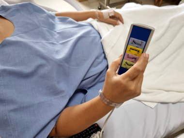 Hasta, tam teşekküllü elektrikli otomatik hastane yatağının uzaktan kumandasına basıyor.