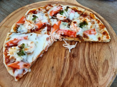 Tahta tabakta ayrılmış lezzetli deniz ürünleri kokteyli pizzası..