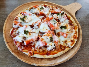 Masadaki lezzetli deniz ürünleri kokteyli pizzası..