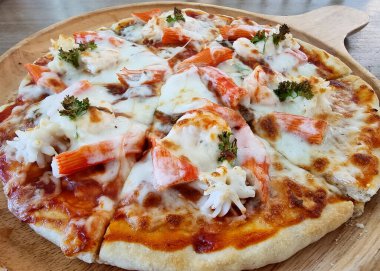 Masadaki lezzetli deniz ürünleri kokteyli pizzası..