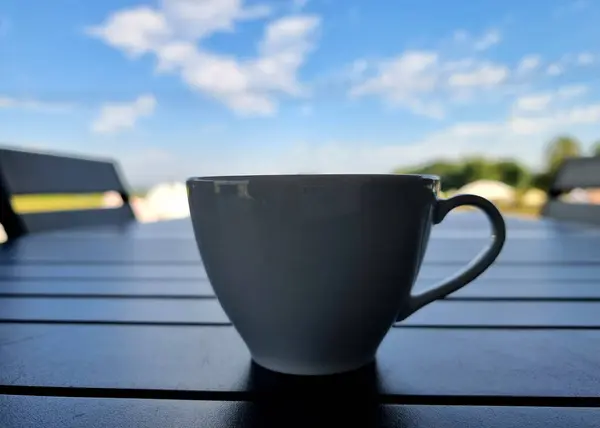 A cup of coffee on a blurred cloud in the blue sky background.